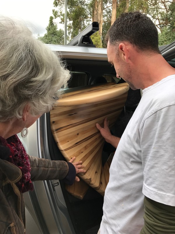 Chris placing a Clever Wood designed and crafted table in back of a vehicle; client touching the wood, too.
